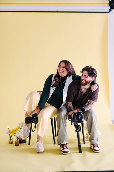 A person sitting on a chair with their partner leaning over their shoulder with joy.