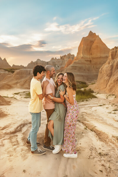 Family of four laugh and smile big while snuggling each other outdoors at the Badlands in South Dakota