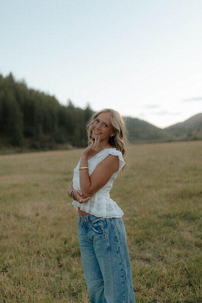 Classic senior portrait of a high school graduate. She's smiling at the camera with her hand gently touching her face.