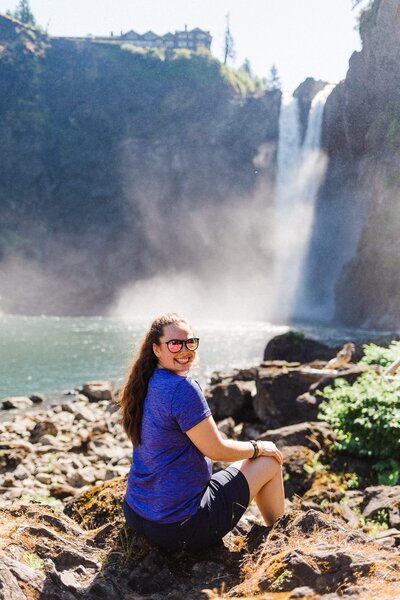 Woman smiling on sunny day with waterfall in the background