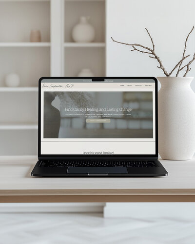 Laptop on a table beside a white vase, showcasing a clean and modern design for a therapist's website.