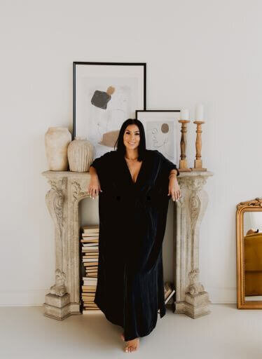 Angelica Ray standing confidently in an elegant studio setting, embodying her role as a speaker and spiritual event facilitator, with a backdrop of modern decor and serene energy