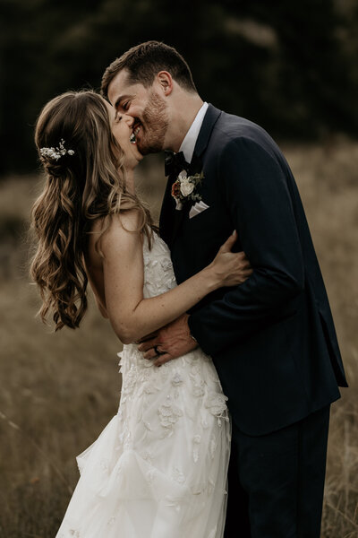 Groom kisses a laughing bride during Estes Park elopement.