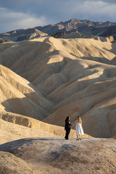 A couple stands in front of a desert landscape in Death Valley