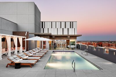 Modern restaurant rooftop pool with the Arizona horizon in the background. White umbrellas and sun loungers on the pool deck for guests to enjoy.