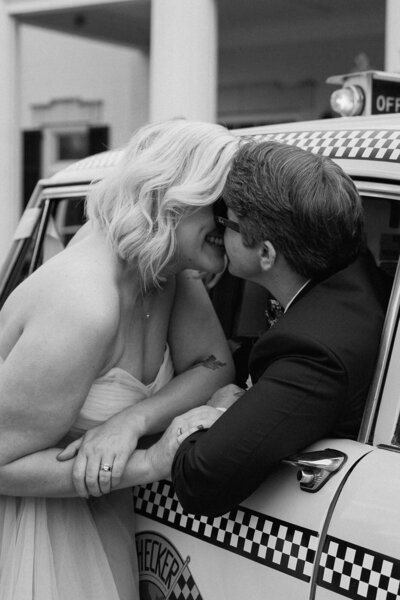 black and white photo of couple smiling with a taxi 
