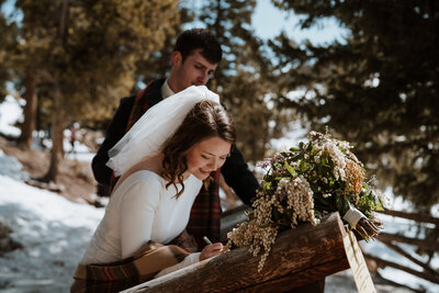 Bride signs marriage license at snowy Sapphire Point elopement in Breckenridge.