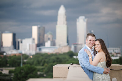 Engaged couple embracing during a romantic Charlotte rooftop proposal with dramatic city skyline in the background, captured by top Charlotte proposal photographer DeLong Photography.
