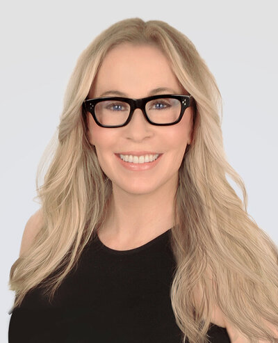 Headshot of Alana Crow, a woman with blonde hair and blue eyes wearing thick-framed black glasses and a black sleeveless top