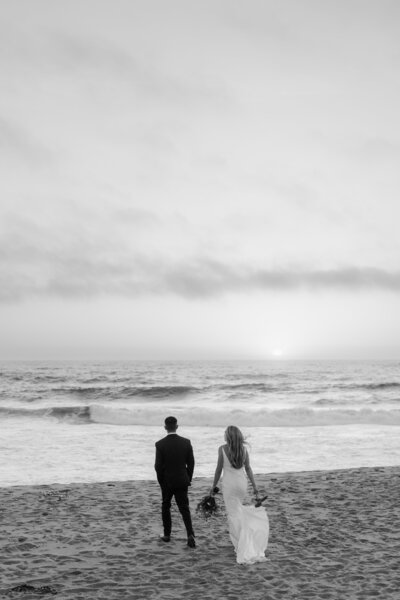 A couple after getting married walking at the beach in santa cruz at sunset