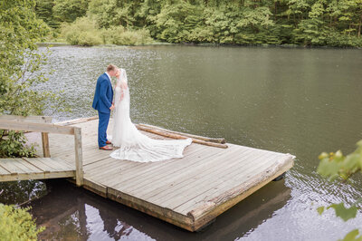 Bride approaches the back of Groom during first look on the water, captured by Lens Love Photography.