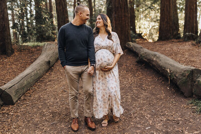 Couple walks holding hands surrounded by the redwoods