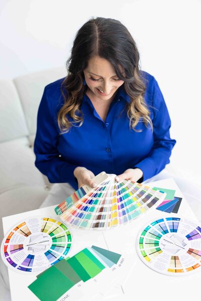 Color psychology expert in royal blue blazer reviewing professional Pantone color fans during strategic brand palette development session