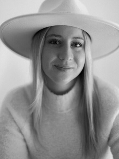 Black and white close up headshot of a woman in a sweater and hat