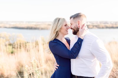 Couple embrace each other during engagement photography session on the side of Minnesota lake.