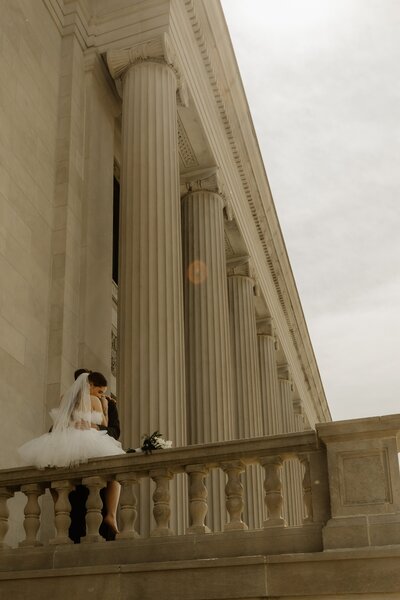 Newlyweds embrace in front of a gorgeous Cedar Rapids courthouse following their elopement ceremony.