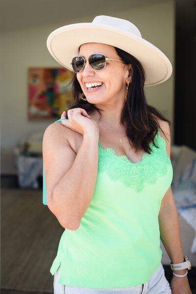 photo of the brand photographer Geise Pinto wearing a hat, sunglasses and a green sleeveless shirt 
