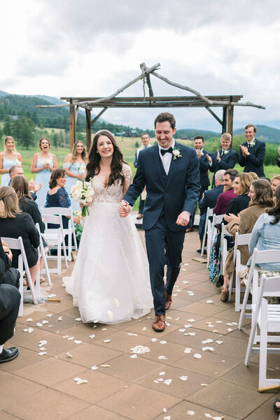 Newly married bride and groom walk down the aisle together after getting married