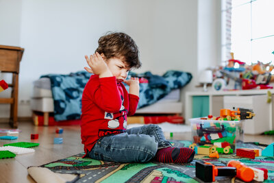 A boy in very bad mood throwing lego blocks