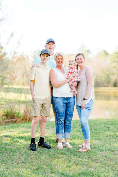 family standing together in a park smiling at camera during summer golden hour