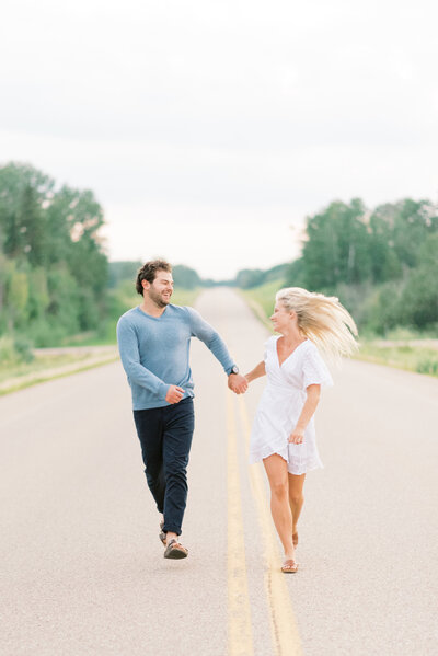 Couple running down 2 lane highway engagement session