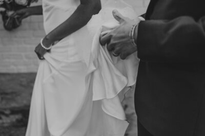 groom holding his brides train and crossing the street