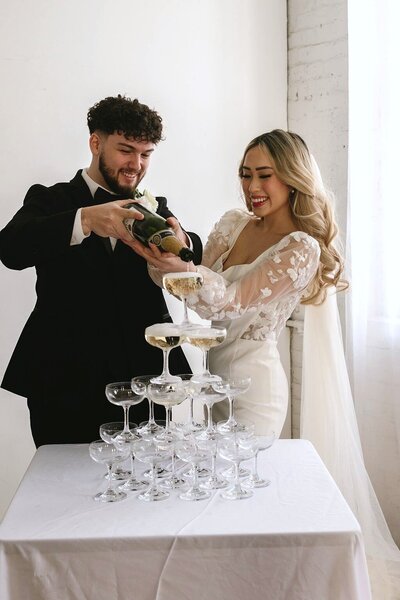 bride and groom pour champagne tower