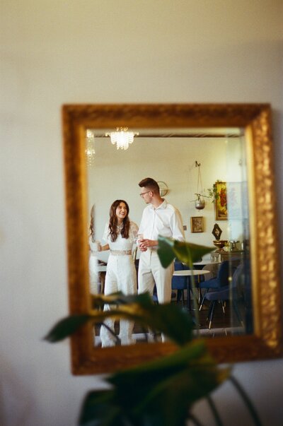 Couple's reflection in a mirror captured walking through a coffee shop on film 