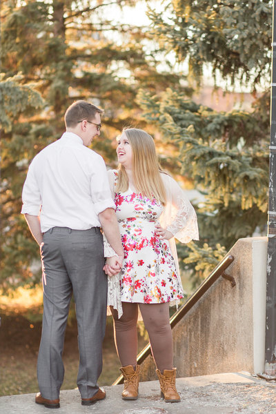Engaged couple holding hands and laughing in black and white