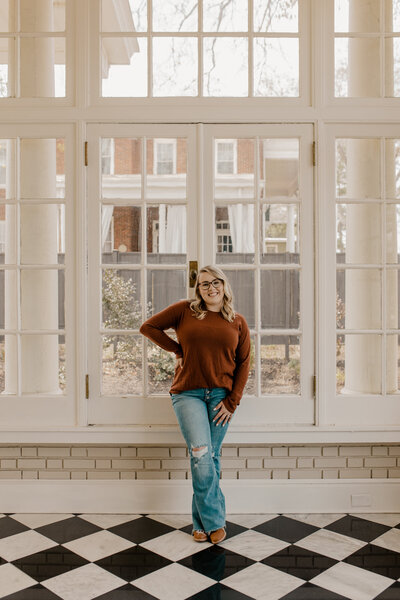 Kayla standing in front a huge window with lots of natural light pouring in