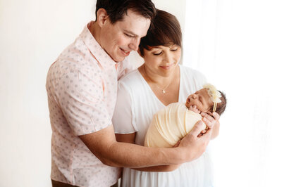 New parents gaze at their infant during Newborn Photography Session in Charleston, SC.