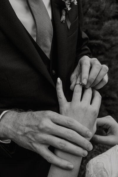 close up of a couple putting their wedding rings on at the ceremony