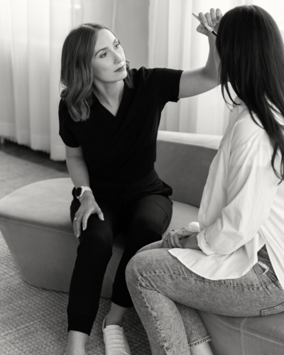 Leigh Anne in a professional consultation with a client in a serene clinic setting, discussing skin health.