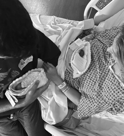 bereaved husband and wife hold stillborn twin babies in knit crochet cradles