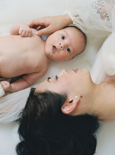 Mom and baby laying on bed for Bay Area newborn photography session.