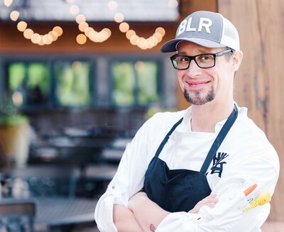 Headshot of male chef in a basement cap and kitchen apron