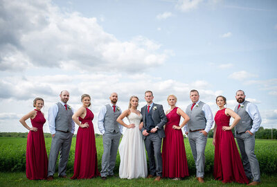 wedding party in red and grey stand in front of field