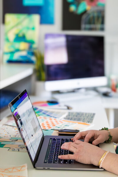 Woman typing on laptop with design patterns on the desk
