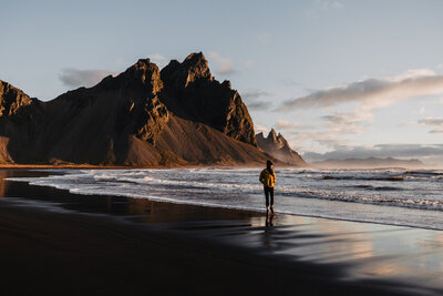 Iceland elopement photographer walking along black sand beach with Vestrahorn in Stokksnes