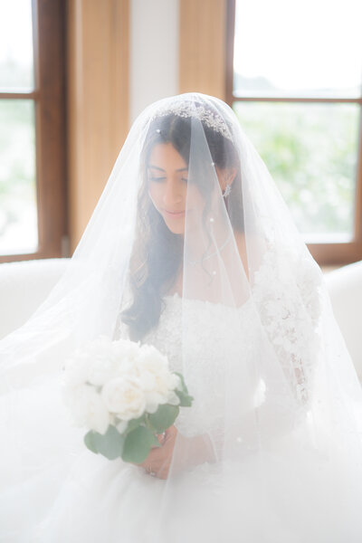 Bride holding bouquet under veil