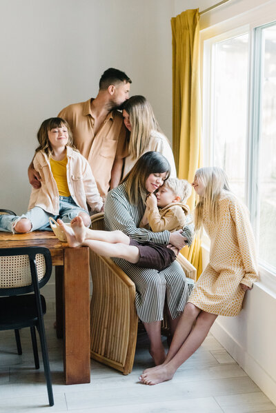 Parents with 4 children sitting and snuggling around a wooden table - Northern Virginia family photographer