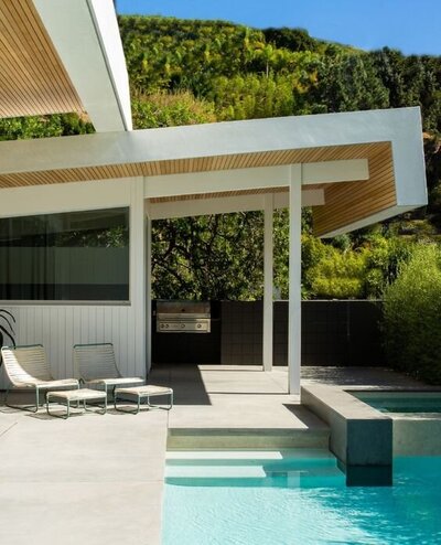 Example of a mid-century modern backyard with a pool and covered patio