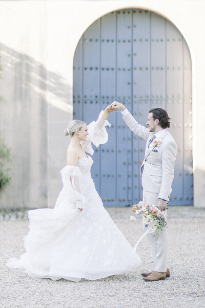 bride and groom dancing outisde in front of blue door