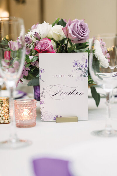 Purple and green summer wedding table number in floral centerpiece arrangement