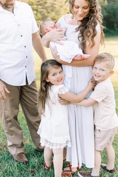 kids hugging mom during outdoor newborn photos in peoria, illinois 