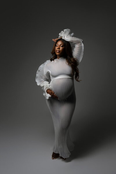 Studio maternity portrait featuring textured sheer robe with rippled sleeves