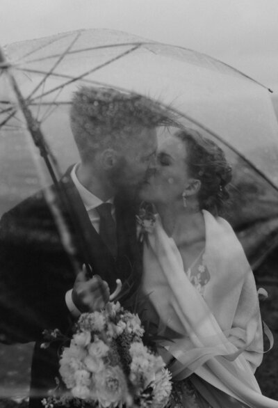 under en dramatisk himmel  på ett fält omringad av hästar står ett brudpar och håller om varandra under sin elopement