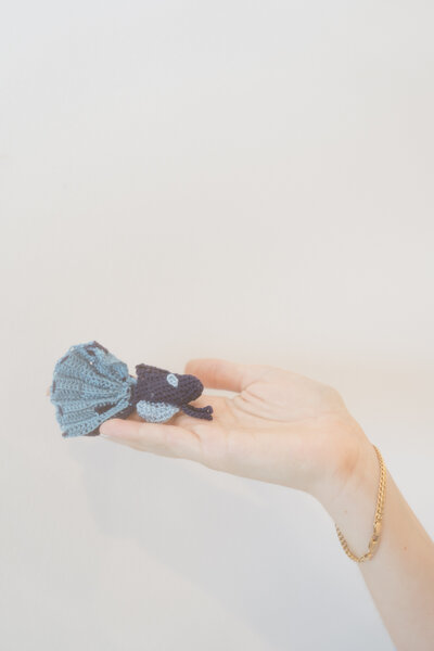 Hand holding up a crochet betta fish