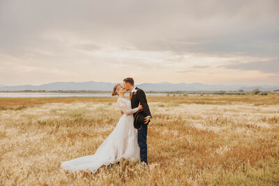 bride and groom embracing in field