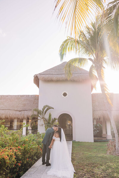 Bride and groom kissing with palm tree in the background